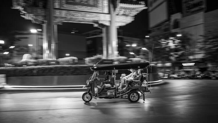Tuk-tuk driving through a city street at night.