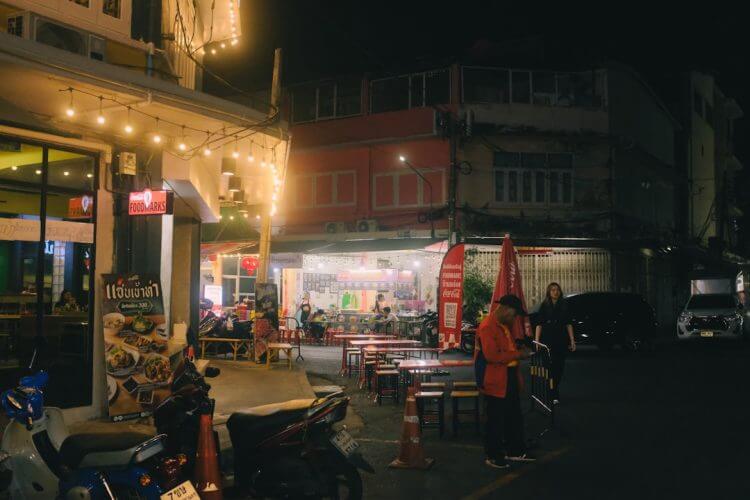 Nighttime street scene with shops and people.
