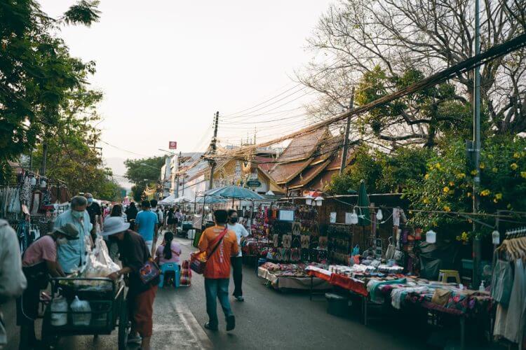 a group of people walking down a street next to a market