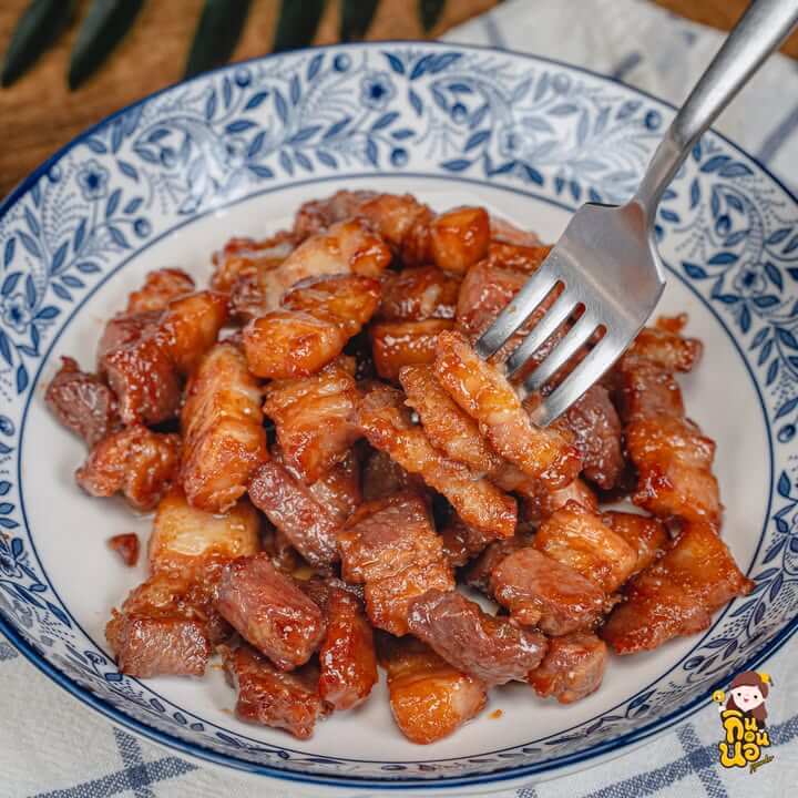 หมูสามชั้นคั่วน้ำปลาหวาน ใช้ส้อมคีบขึ้นเห็นซอสเคลือบเงาวับ