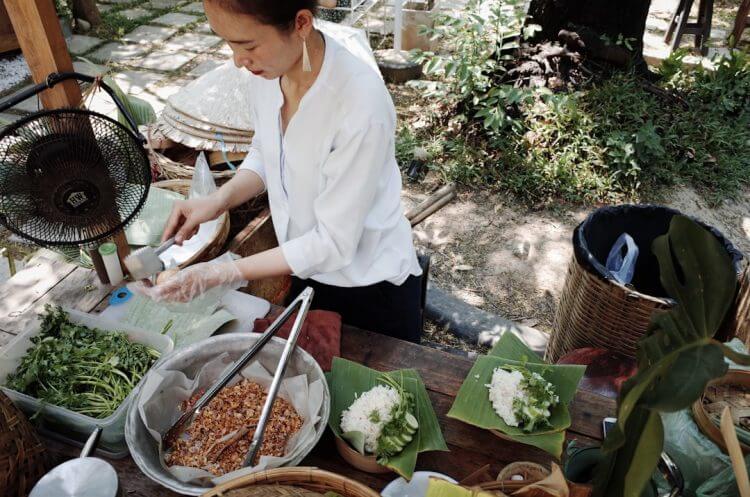 Woman prepares food outdoors at a market.