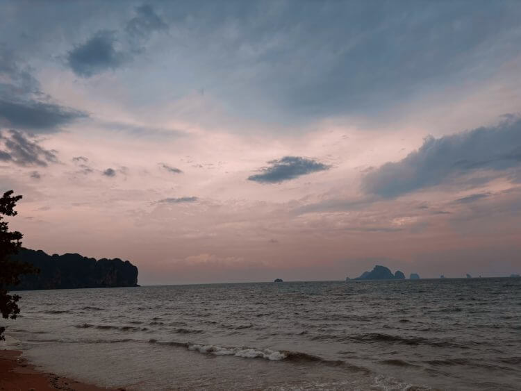 A view of a beach at sunset with a boat in the distance