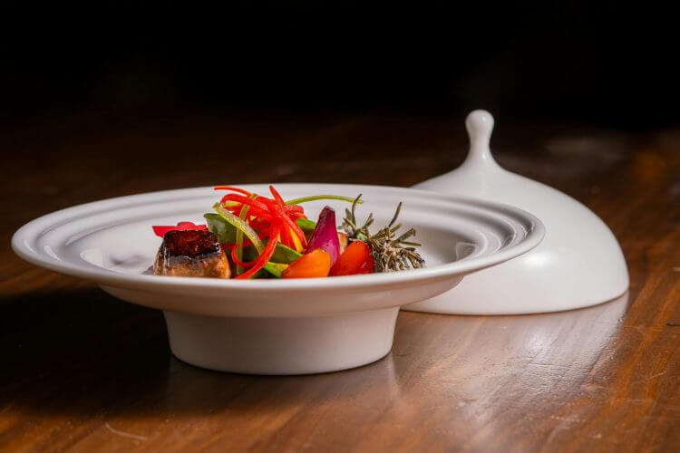 Elegant gourmet dish with vibrant vegetables elegantly arranged in a white plate.