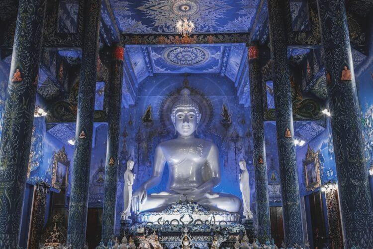 A large silver buddha statue inside a blue temple