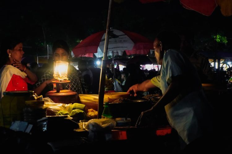 Street vendor preparing food under lantern light at night.
