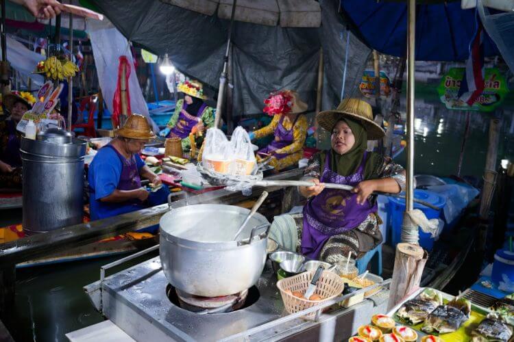 Vendors prepare food at a bustling floating market.