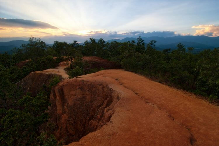 Explore a stunning red rock canyon trail under a vibrant sunset sky.