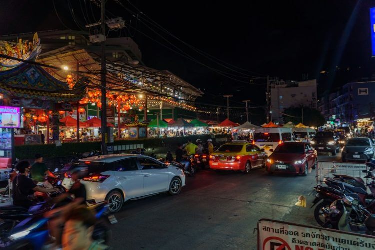 Busy city street at night with food vendors.