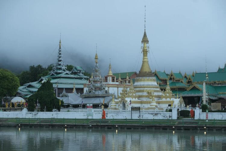 Wat Chong Kham temple surrounded by mist with reflections on the pond at Mae Hong Son.