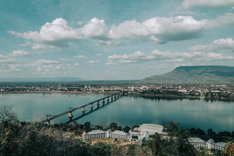 A picturesque bridge spans the Mekong River in a tranquil Laotian landscape.