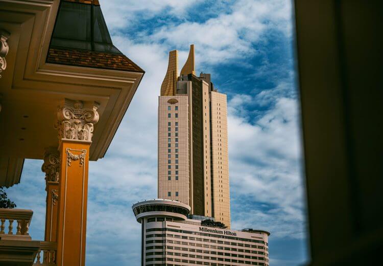 Stunning view of the Millennium Hilton tower in Bangkok with vibrant cloudy skies.