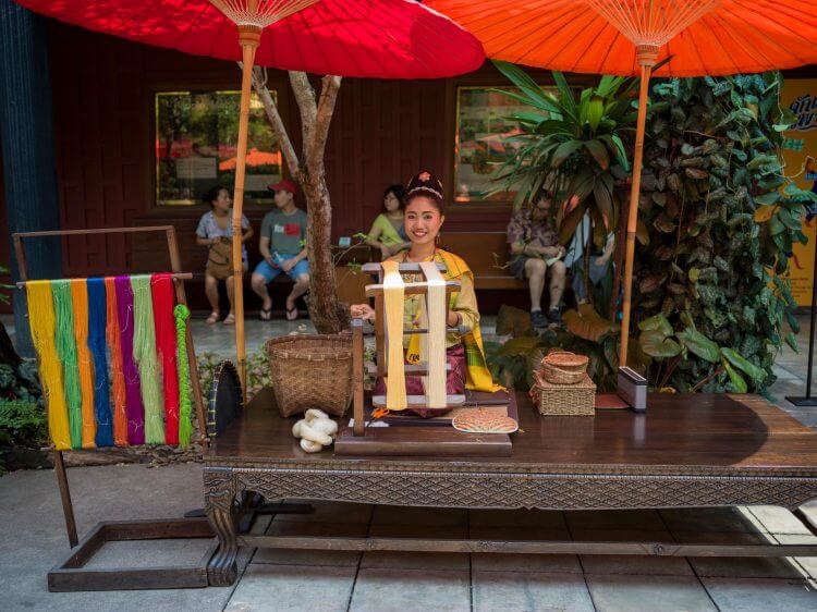 A woman demonstrating traditional Thai silk weaving at Jim Thompson House in Bangkok, Thailand.