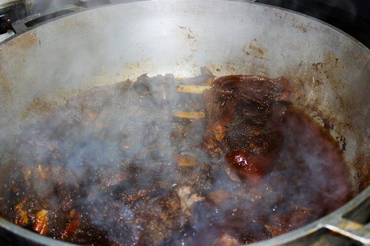 Meat simmering in a pot with steam rising.