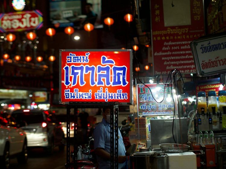 A bustling urban street at night with illuminated signs and vibrant market life.
