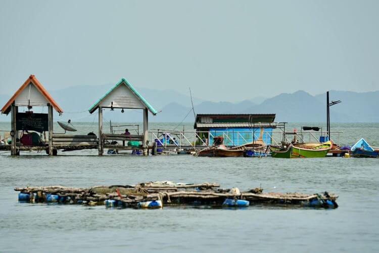Colorful fishing village with huts and boats on a peaceful waterfront setting.
