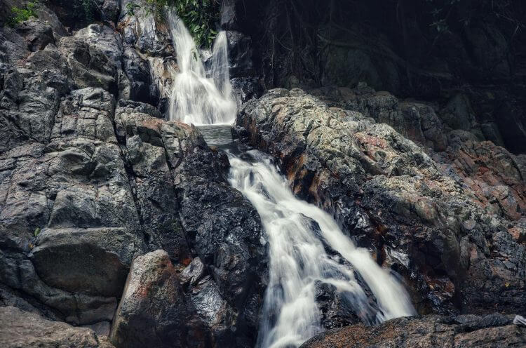 A peaceful waterfall cascading over rocky formations in Koh Samui, Thailand, creating a tranquil natural scene.