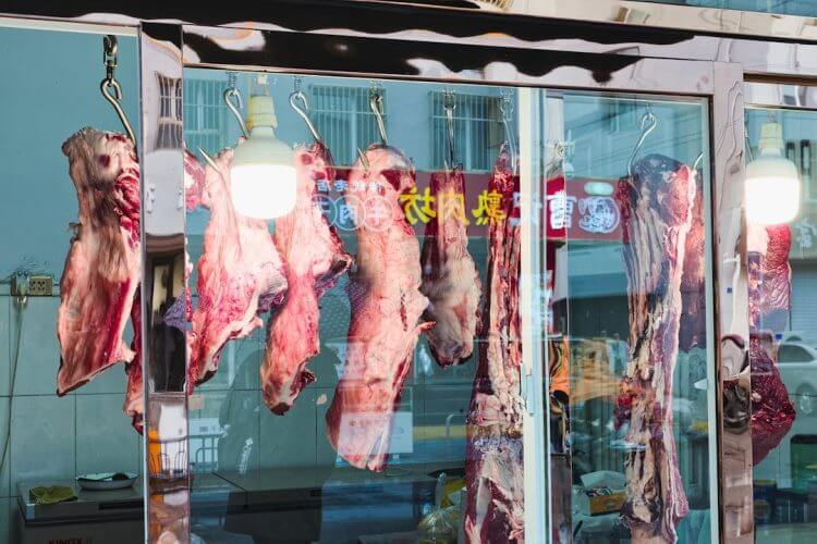 Raw meat hanging in a butcher shop window.