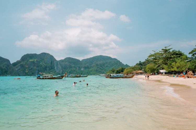 Beachgoers enjoy a beautiful tropical paradise with boats.