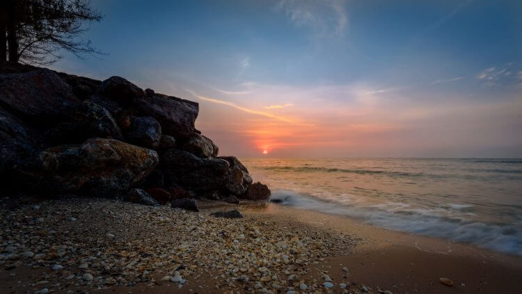 Stunning beach sunset with rocks at Tambon Bang Kao, Thailand.