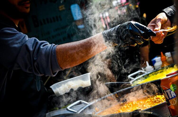 a person in black gloves cooking food on a grill