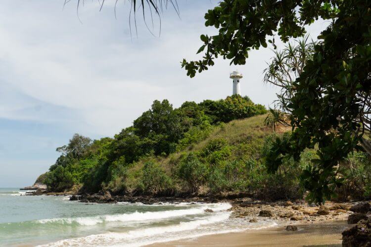 A sandy beach with a light house in the distance