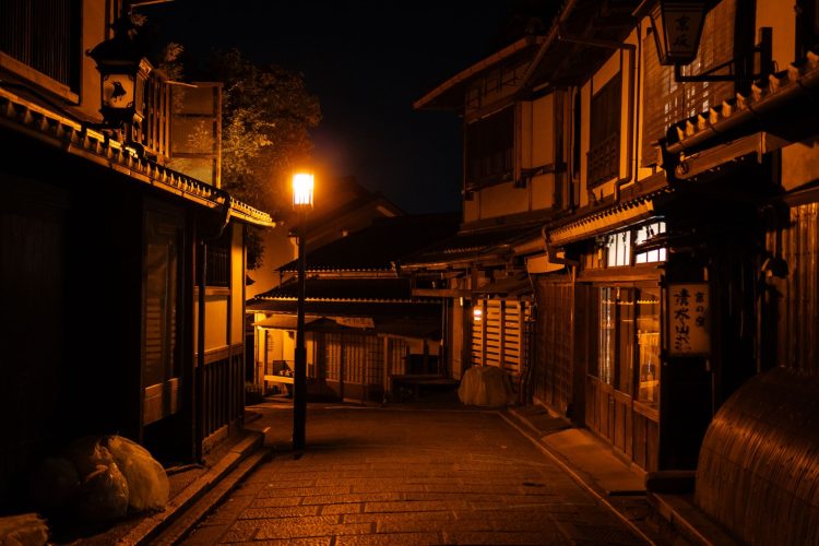 Traditional Japanese street illuminated by warm streetlights, creating a tranquil night scene.