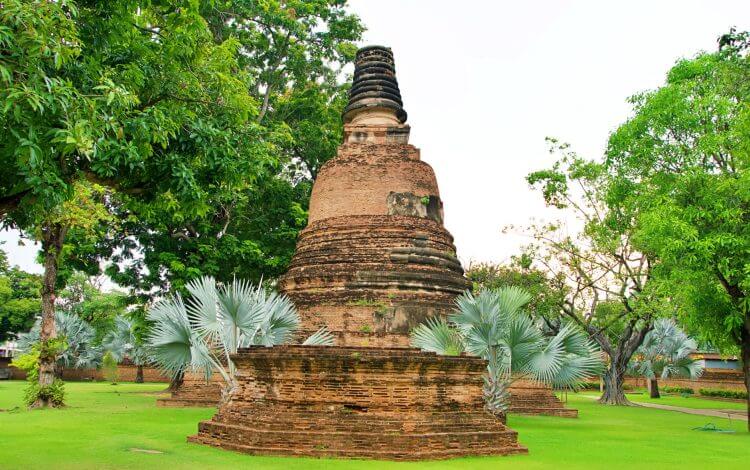 Explore the ancient chedi surrounded by lush greenery in Ayutthaya Historical Park, Thailand.