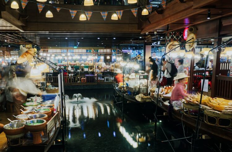 People shopping at a bustling floating market at night.
