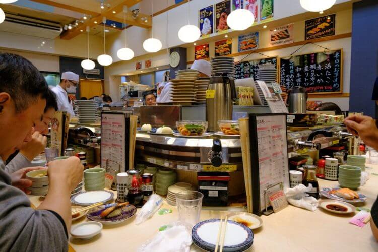 People eating at a busy sushi restaurant counter