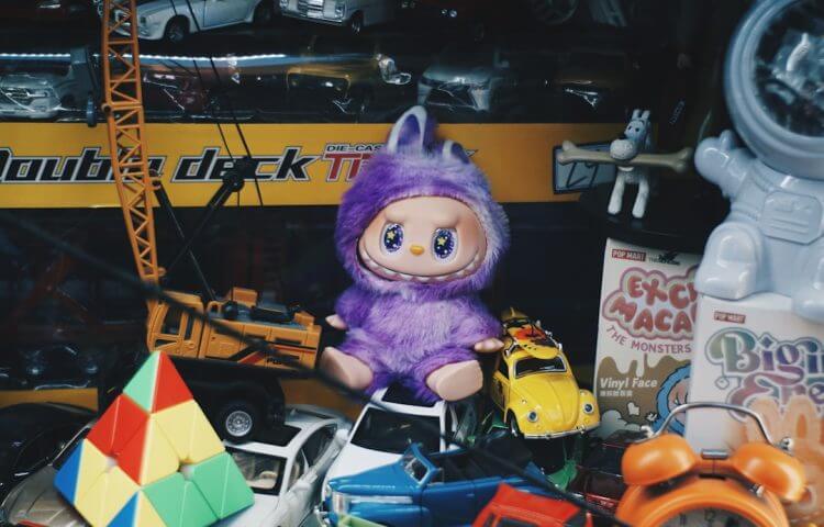 Purple fuzzy toy sits among other toys.
