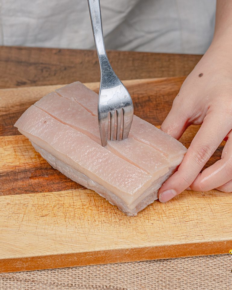 หมูกรอบหม้อทอด ขั้นที่ 6: ใช้ส้อมจิ้มหนังหมูให้ถี่และทั่วทั้งชิ้น รวมถึงขอบชิ้นและในร่องที่บั้งไว้