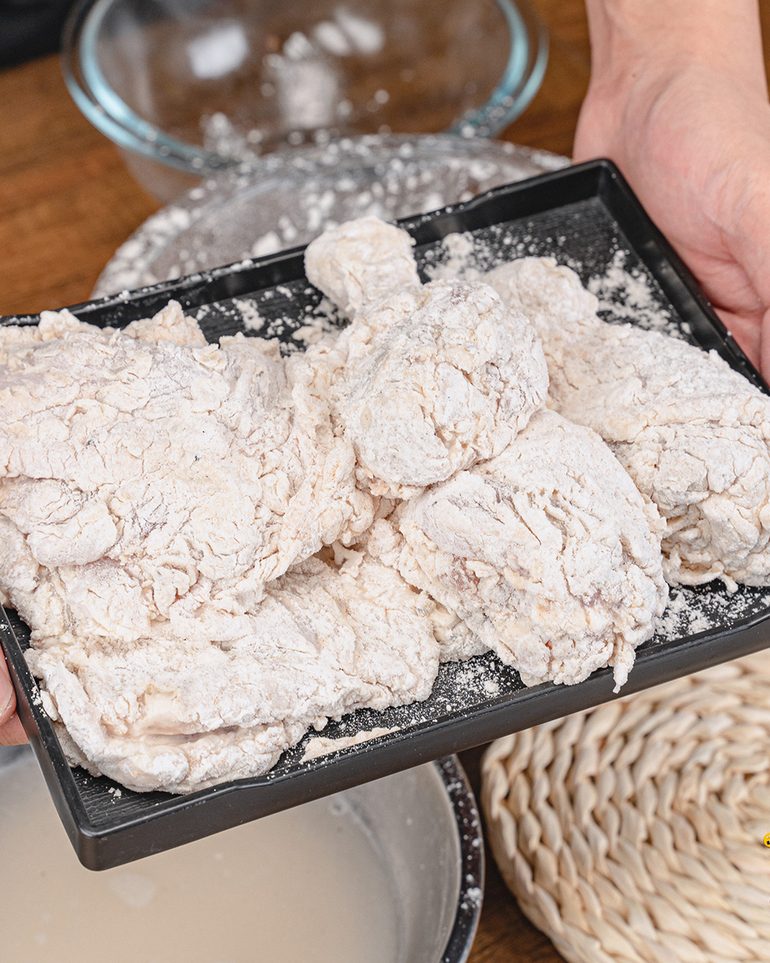 ไก่ทอดกร๊อบๆ ขั้นที่ 7: คลุกแป้งแห้งปิดท้าย กำมือบีบรอบชิ้นไก่ให้แป้งเกาะเป็นก้อนเล็กๆ ขรุขระ…