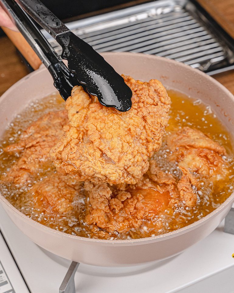 ไก่ทอดกร๊อบๆ ขั้นที่ 11: ใช้ที่คีบยกไก่ขึ้น พักบนตะแกรงให้สะเด็ดน้ำมันประมาณ 3–5 นาที แล้วทอดชุดถัดไป…