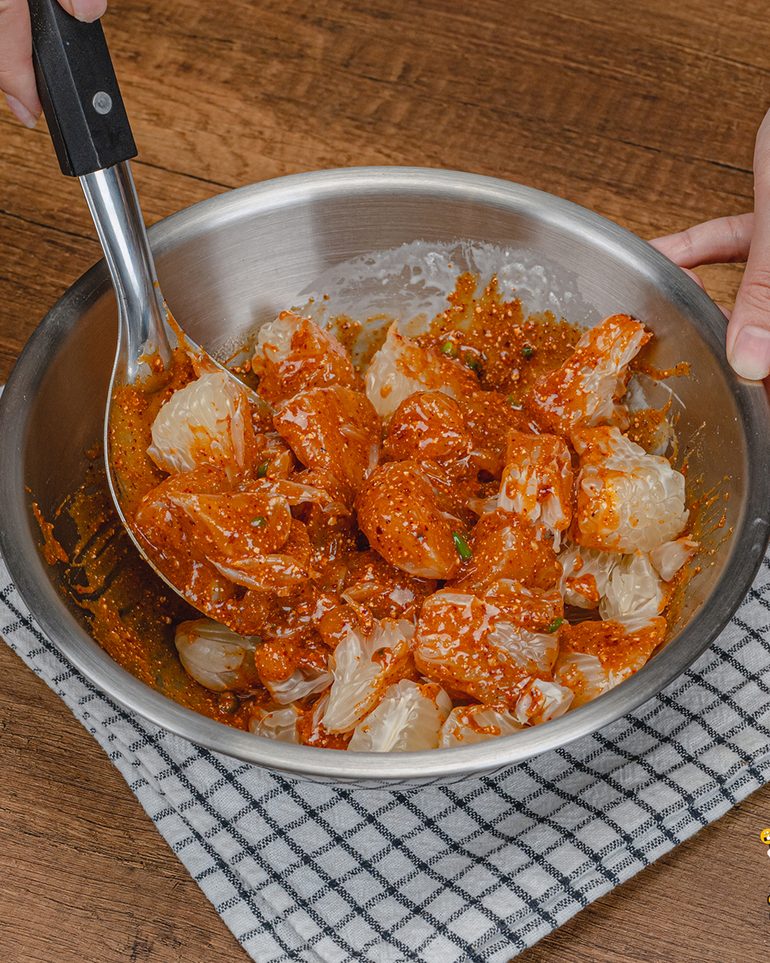 ยำข้าวคั่วส้มโอ ขั้นที่ 5: ใส่ส้มโอ ใช้ทัพพีตักจากก้นอ่างแล้วพลิกขึ้นเบาๆ พอน้ำยำเคลือบเนื้อส้มโอทั่วก็หยุด…