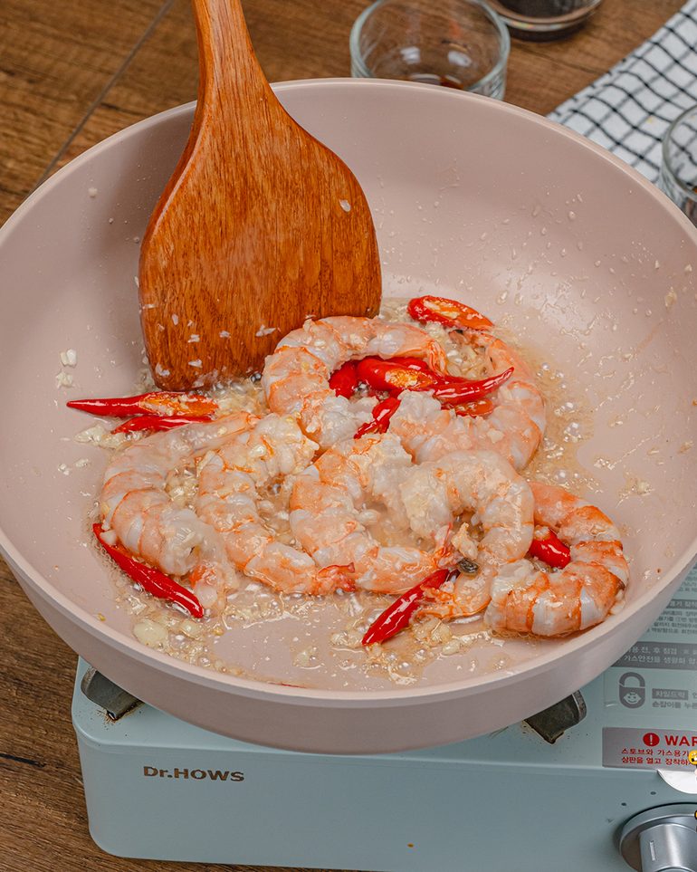 ผัดชะอมกุ้งไข่เค็ม ขั้นที่ 3: ใส่กุ้งลงไป ผัดจนกุ้งเริ่มเปลี่ยนเป็นสีส้มแต่ยังไม่สุกทั่ว ราว 1–2 นาที