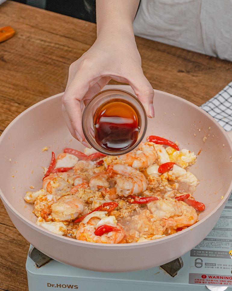 ผัดชะอมกุ้งไข่เค็ม ขั้นที่ 6: ปรุงรสด้วยซีอิ๊วขาว ซอสปรุงรส น้ำมันหอย และน้ำตาล ผัดพอเข้ากันดีแล้วชิม…