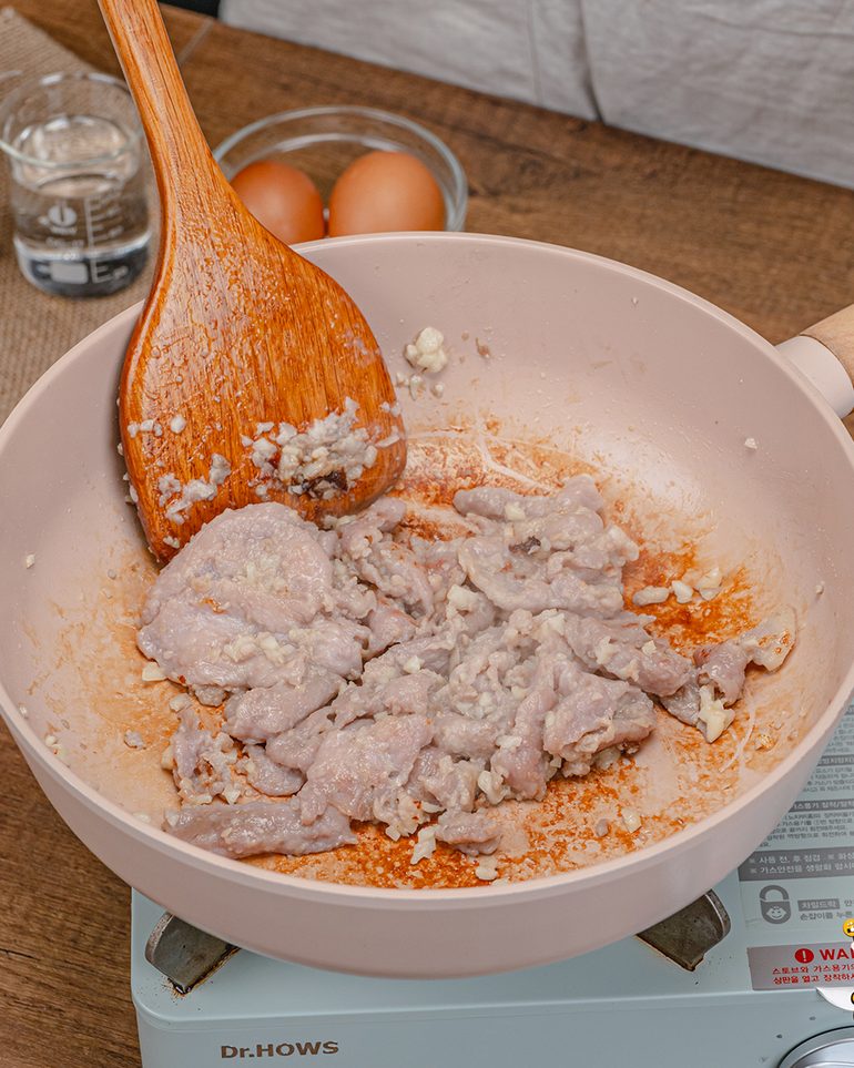 สุกี้แห้งหมูหมักน้ำมันงา ขั้นที่ 3: ใส่หมูหมัก เกลี่ยให้ชิ้นหมูแยกกัน ผัดจนหมูเริ่มสุก…