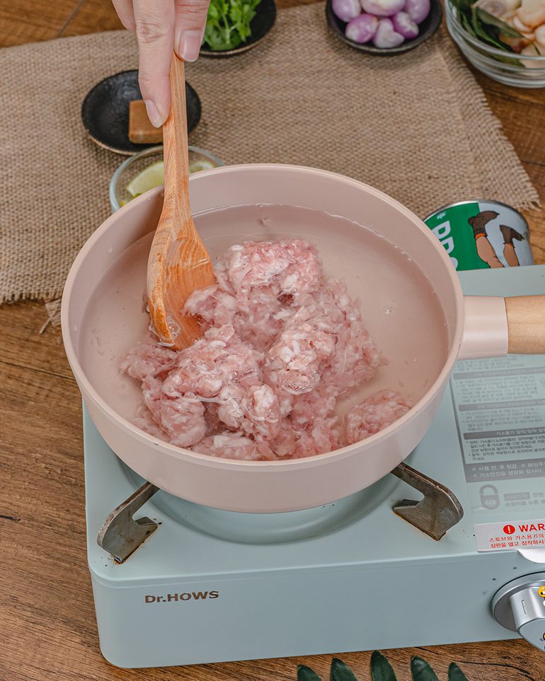 ต้มแซ่บหมูสับ ขั้นที่ 2: ใส่หมูสับลงในน้ำ ใช้ทัพพีเขี่ยและคนจนหมูแตกตัวเป็นเม็ดเล็กๆ ไม่มีก้อนใหญ่ค้าง