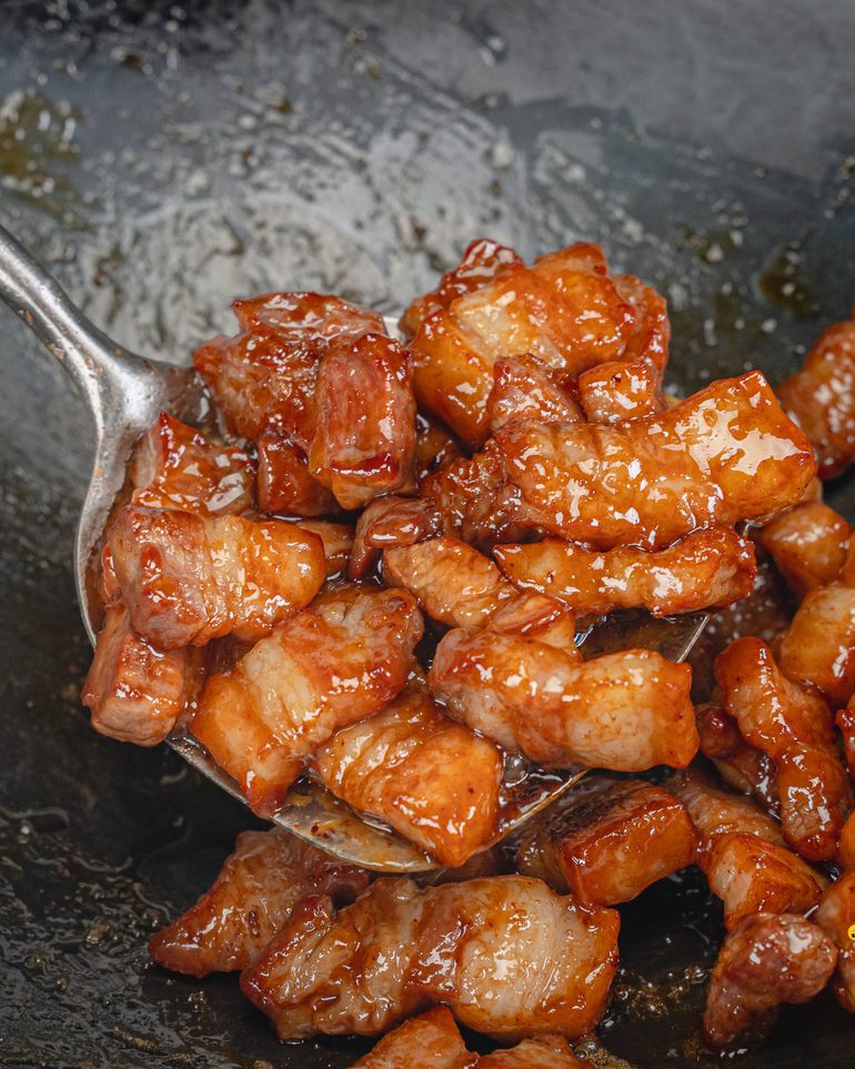หมูสามชั้นคั่วน้ำปลาหวาน ขั้นที่ 7: ผัดคลุกประมาณ 2–3 นาที จนน้ำตาลเหนียวเคลือบเงาทั่วทุกชิ้น…