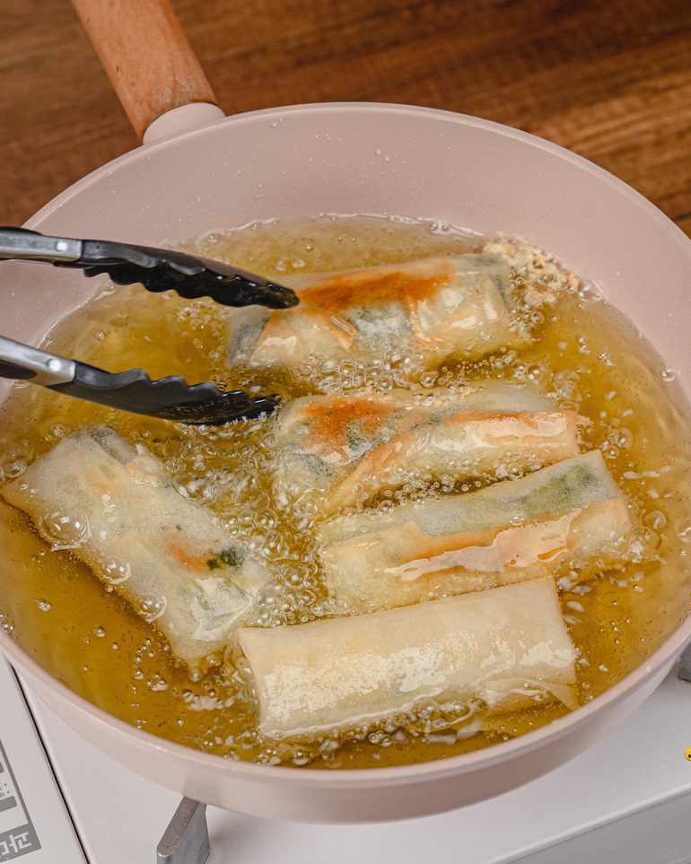 ปอเปี๊ยะผักโขมแฮมชีส ขั้นที่ 9: ใส่ปอเปี๊ยะลงทอดทีละ 4–5 ม้วน ใช้ที่คีบกลับด้านเป็นระยะ ทอดประมาณ 4–6…